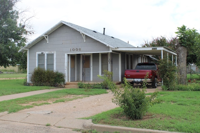 1008 10th St, Ballinger, TX 76821 - view of front facade with a front yard, driveway, an attached carport, and a porch