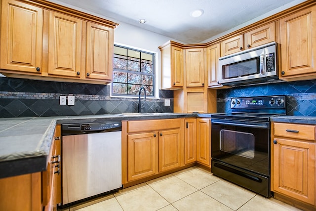 1617 Idaho Ave, San Angelo, TX 76904 - kitchen with appliances with stainless steel finishes, light tile patterned floors, dark countertops, and backsplash