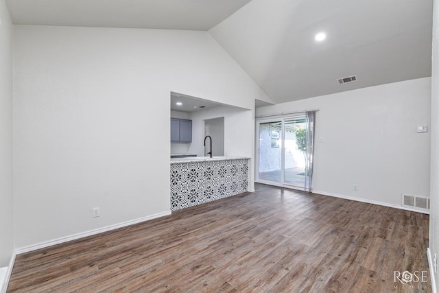 unfurnished living room with wood-type flooring and high vaulted ceiling