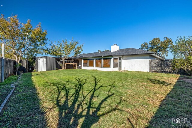 rear view of house featuring a storage shed and a yard