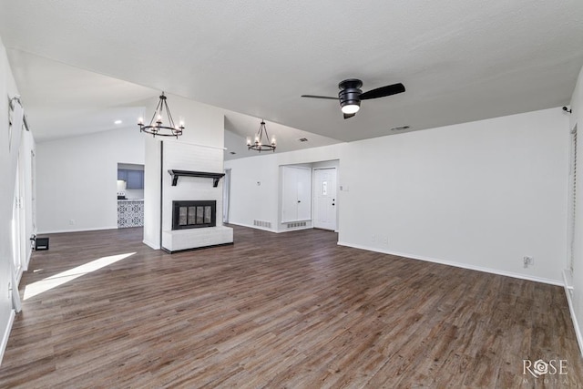 unfurnished living room featuring a brick fireplace, ceiling fan with notable chandelier, dark wood-type flooring, and vaulted ceiling