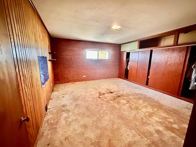 unfurnished bedroom featuring carpet flooring and brick wall