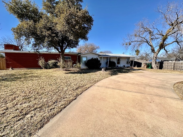 ranch-style home with concrete driveway and fence