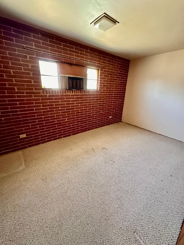 carpeted empty room featuring a wealth of natural light and brick wall