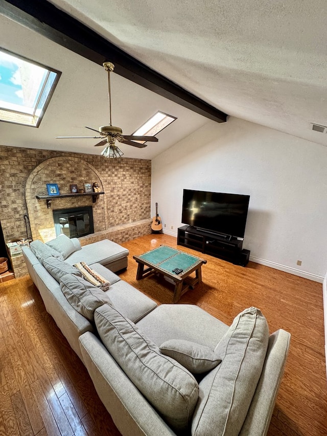5214 Green Valley Trl, San Angelo, TX 76904 - living room with a skylight, ceiling fan, a textured ceiling, a brick fireplace, and wood finished floors