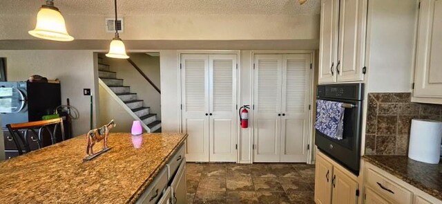 1210 Elizabeth St, Rankin, TX 79778 - kitchen with oven, a textured ceiling, dark stone counters, decorative light fixtures, and white cabinets