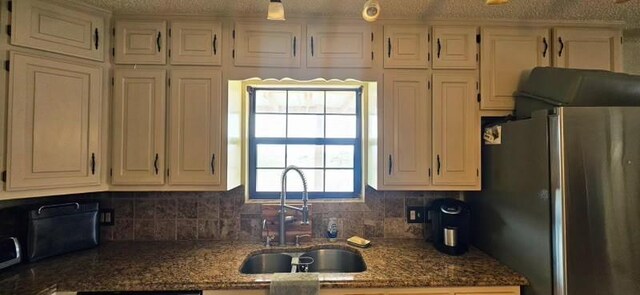 1210 Elizabeth St, Rankin, TX 79778 - kitchen with freestanding refrigerator, a sink, decorative backsplash, dark stone countertops, and white cabinets