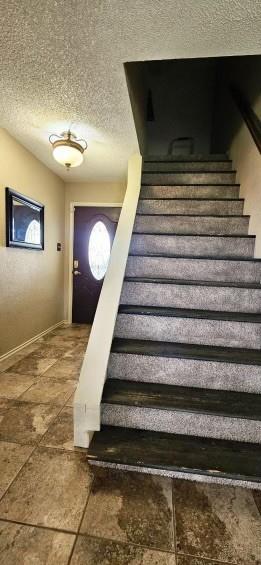 1210 Elizabeth St, Rankin, TX 79778 - stairs with a textured ceiling and baseboards