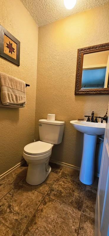 1210 Elizabeth St, Rankin, TX 79778 - half bathroom featuring toilet, a textured ceiling, a textured wall, and a sink