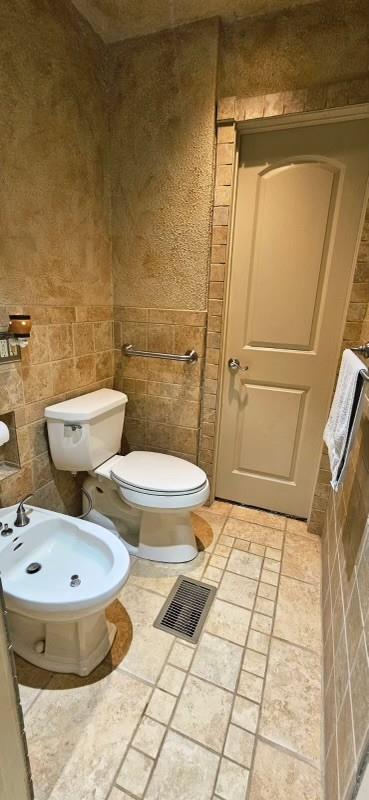 1210 Elizabeth St, Rankin, TX 79778 - bathroom featuring toilet, a bidet, and tile walls