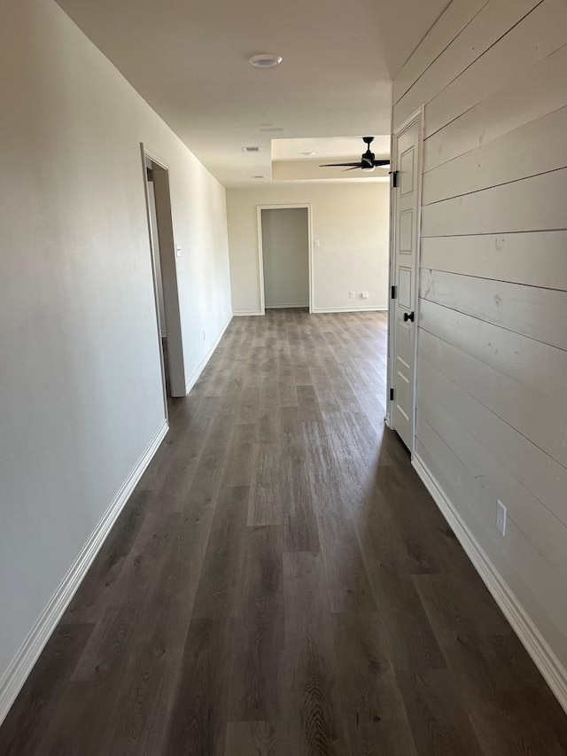 hallway with dark wood-type flooring and wooden walls