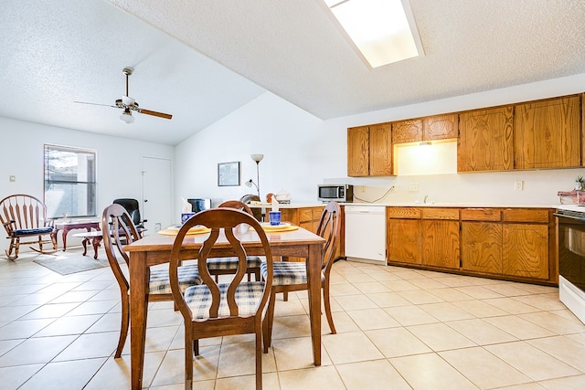 dining space featuring sink, vaulted ceiling, a textured ceiling, light tile patterned floors, and ceiling fan