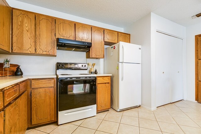 kitchen with white fridge, electric range oven, light tile patterned floors, and a textured ceiling