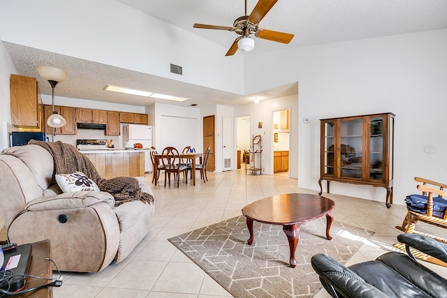 tiled living room with ceiling fan, high vaulted ceiling, and a textured ceiling