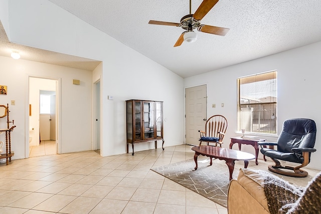 living area featuring ceiling fan, high vaulted ceiling, a textured ceiling, and light tile patterned floors