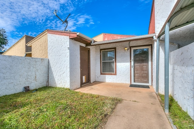 entrance to property featuring a yard and a patio