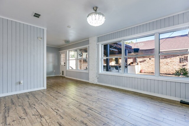 empty room with an inviting chandelier, hardwood / wood-style flooring, and a healthy amount of sunlight