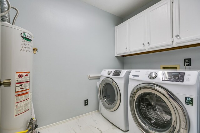 clothes washing area featuring cabinets, washing machine and clothes dryer, and gas water heater