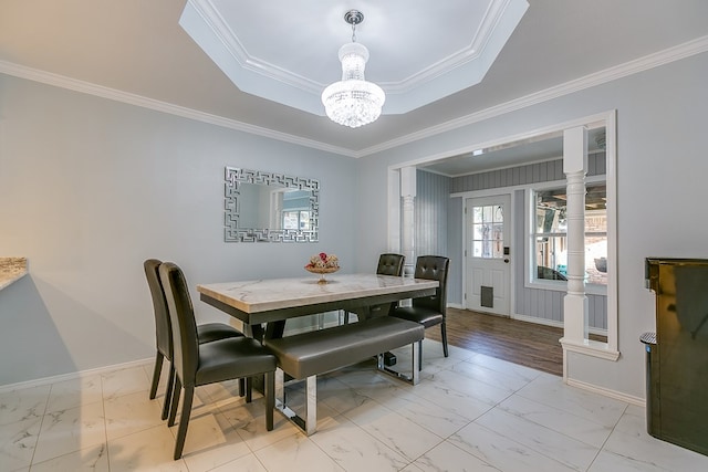 dining space featuring a notable chandelier, a tray ceiling, and ornamental molding