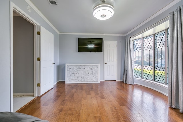 unfurnished living room featuring hardwood / wood-style floors and crown molding