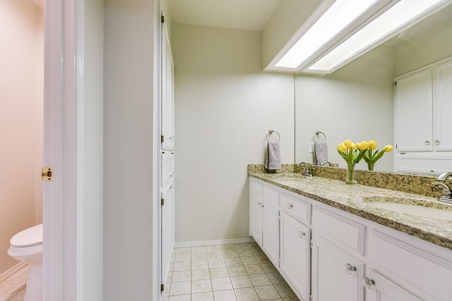 bathroom with tile patterned floors, vanity, toilet, and a skylight