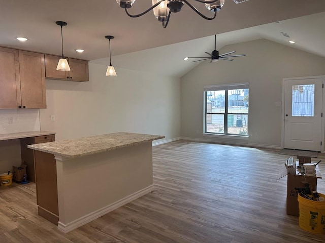 kitchen featuring vaulted ceiling, hanging light fixtures, dark hardwood / wood-style flooring, light stone countertops, and ceiling fan with notable chandelier