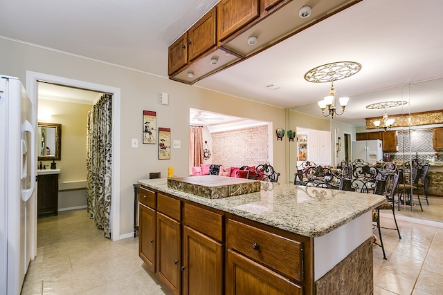 4918 Blue Ridge Trl, San Angelo, TX 76904 - kitchen featuring freestanding refrigerator, a notable chandelier, a kitchen island, and light tile patterned floors