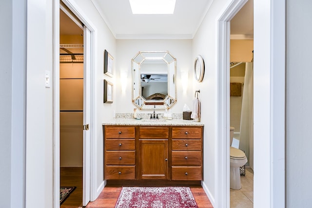 4918 Blue Ridge Trl, San Angelo, TX 76904 - bathroom featuring vanity, toilet, wood finished floors, a spacious closet, and ornamental molding