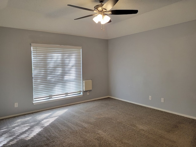 carpeted spare room with a ceiling fan and baseboards