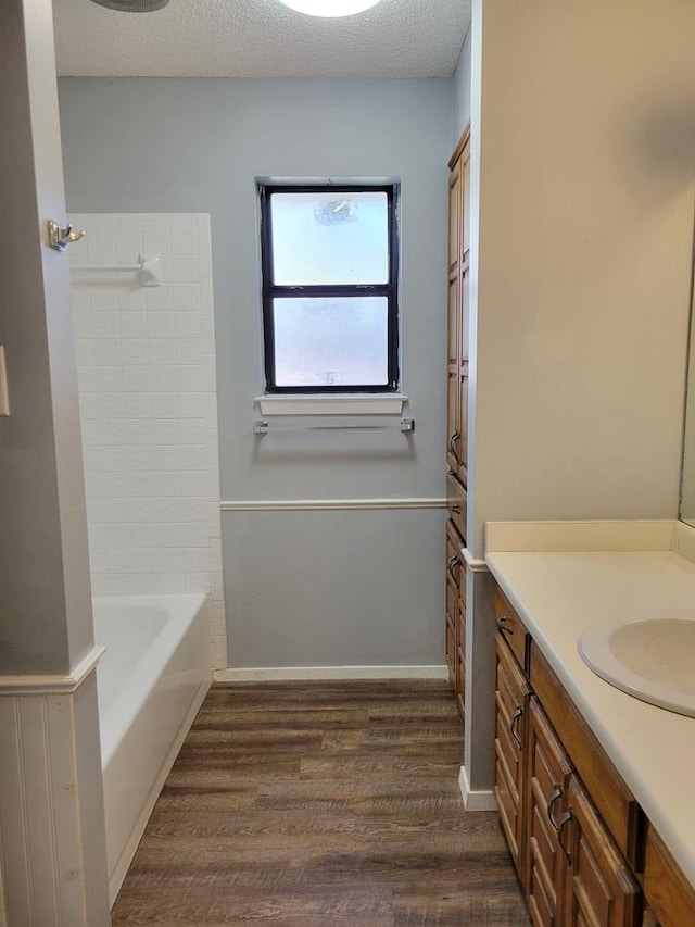 bathroom with baseboards, shower / washtub combination, vanity, wood finished floors, and a textured ceiling