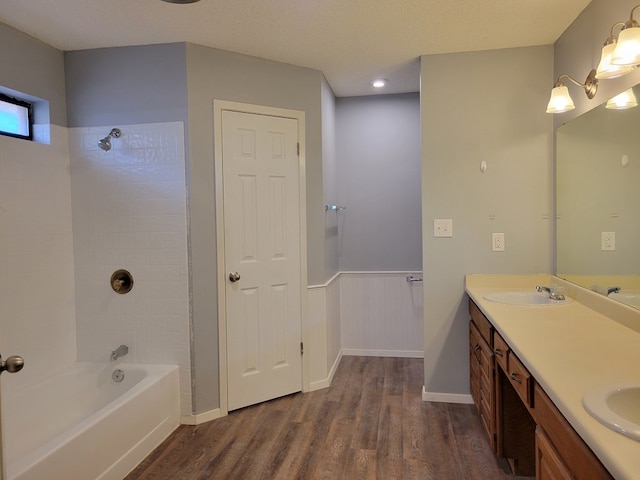 bathroom featuring wood finished floors, double vanity, a sink, bathtub / shower combination, and a textured ceiling