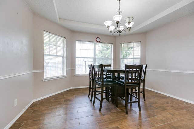 dining space with plenty of natural light, a notable chandelier, and a tray ceiling