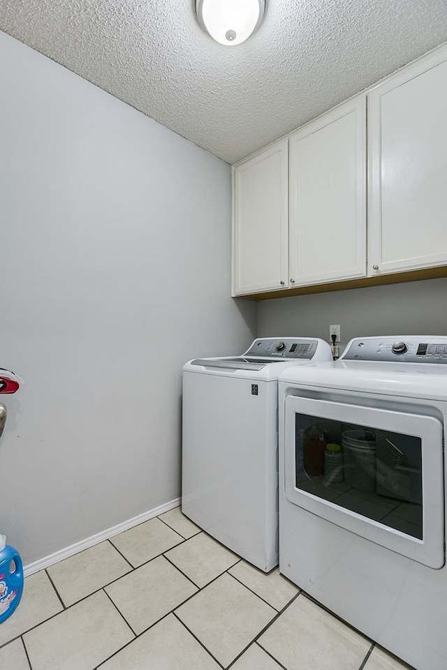 washroom featuring cabinets, light tile patterned floors, a textured ceiling, and washer and clothes dryer