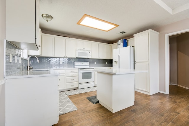 kitchen with sink, white appliances, a center island, and white cabinets