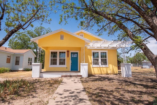 bungalow-style house with stucco siding and fence