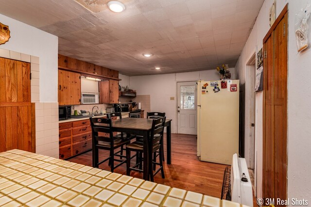 kitchen with sink, stainless steel electric range, tile counters, dark hardwood / wood-style flooring, and white fridge