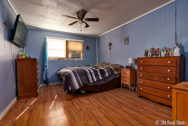 bedroom with dark wood-type flooring, ceiling fan, cooling unit, wooden walls, and a textured ceiling