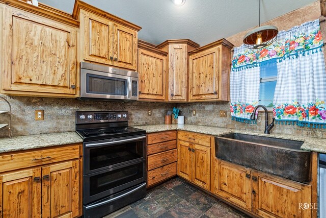 kitchen featuring double oven range, light stone countertops, sink, and backsplash