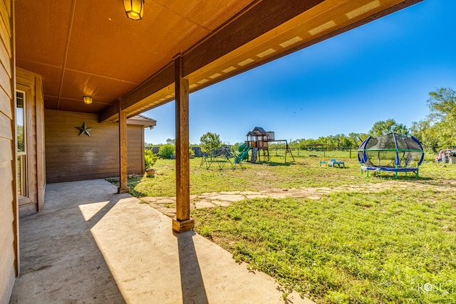 view of yard featuring a trampoline, a patio area, and a playground