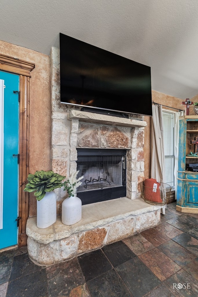 interior details with a stone fireplace and a textured ceiling