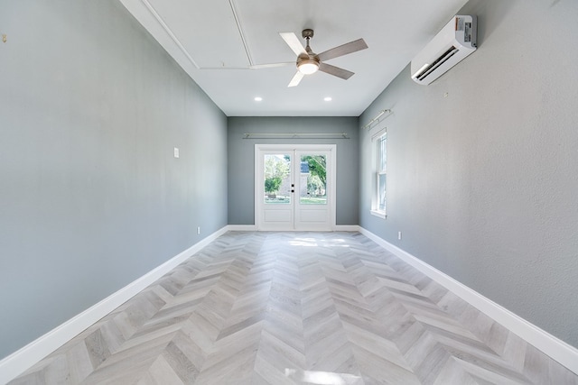 spare room with an AC wall unit, french doors, baseboards, attic access, and ceiling fan