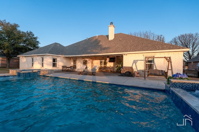 view of swimming pool with a pool with connected hot tub, a patio, and fence