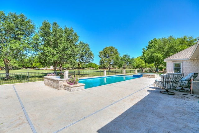 view of swimming pool featuring a pool with connected hot tub, a patio, and fence