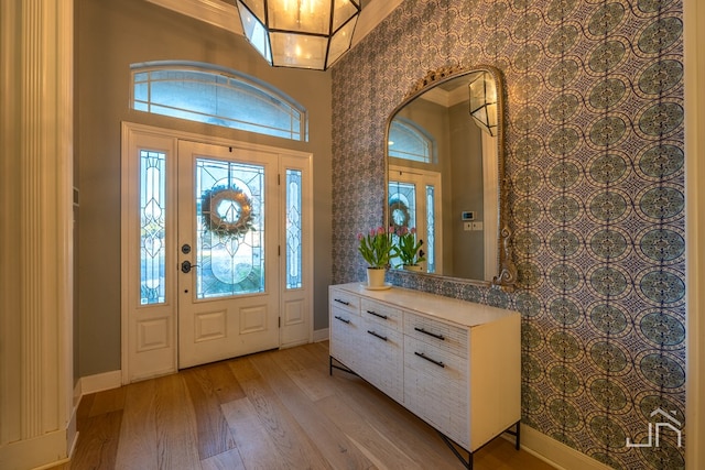 foyer entrance featuring a towering ceiling and light hardwood / wood-style flooring