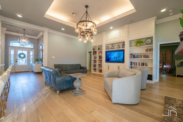 living room featuring an inviting chandelier, crown molding, a raised ceiling, and light hardwood / wood-style flooring