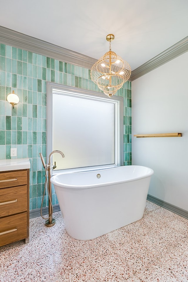 full bathroom with crown molding, speckled floor, a freestanding bath, baseboards, and a notable chandelier