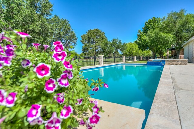 view of pool with a pool with connected hot tub, a patio area, and fence