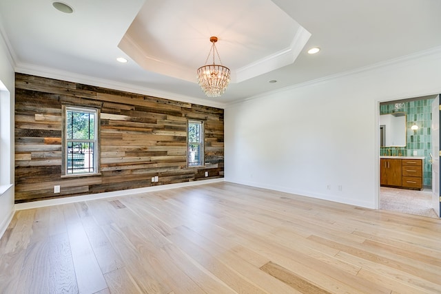 unfurnished room featuring light wood-style floors, a healthy amount of sunlight, and wood walls