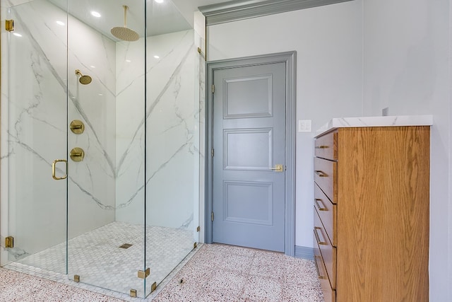 bathroom with speckled floor and a marble finish shower