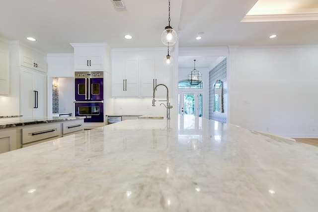 kitchen featuring a sink, visible vents, crown molding, light stone countertops, and double oven